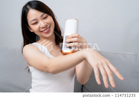 A beautiful woman is epilating and removing hair using an IPL laser hair removal epilator device. A beautiful woman is epilating and removing hair using an IPL laser hair removal epilator device. 114731235