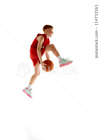 Full-length image of active teen boy in red uniform, basketball player training, playing isolated on white studio background 114733561