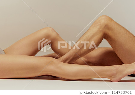 Male and female legs against warm grey background. Skincare products, focusing on the smooth and healthy appearance of the skin. Male and female legs against warm grey background. Skincare products, focusing on the smooth and healthy appearance of the skin. 114733701