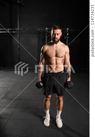 Man performing dumbbell lunge, holding dumbells in both hands. Routine workout for physical and mental health. 114734235