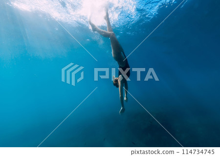Woman dive to the sea bottom in blue ocean. Free diving with beautiful girl in ocean 114734745