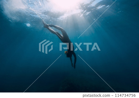 Silhouette of woman dive in transparent sea. Freediving with slim girl in ocean and sun rays Silhouette of woman dive in transparent sea. Freediving with slim girl in ocean and sun rays 114734756