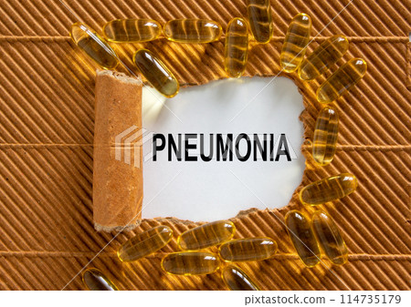 The text 'pneumonia' appearing behind torn brown paper. Yellow pills. Concept. Beautiful background. 114735179