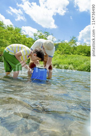 Father and son playing in the river with underwater viewing glasses 114736490