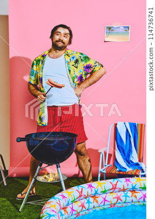 Man posing in studio with inflatable pool and cooking barbeque sausages for picnic. Summer activities. Ad 114736741