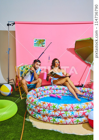Man fishing bottles from inflatable pool and woman sitting next to him in swimsuit sunbathing. Trendy retro colors. Man fishing bottles from inflatable pool and woman sitting next to him in swimsuit sunbathing. Trendy retro colors. 114736790