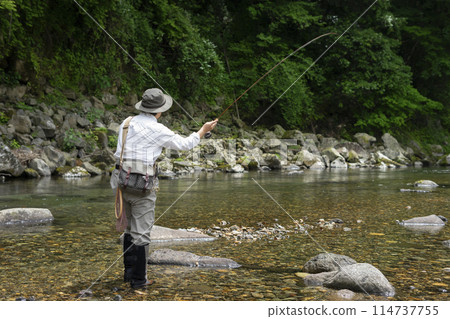 A man fishing in a mountain stream in early summer 114737755
