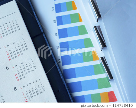 桌上放置的圖表、日曆、文件和筆記本 114738410