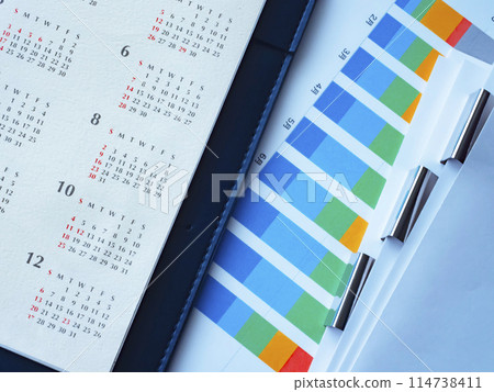 桌上放置的圖表、日曆、文件和筆記本 114738411
