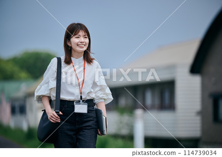拿著電腦和筆記型電腦走路的年輕女子 拿著電腦和筆記型電腦走路的年輕女子 114739034