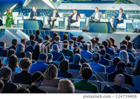 Large business conference with speakers and audience members 114739408