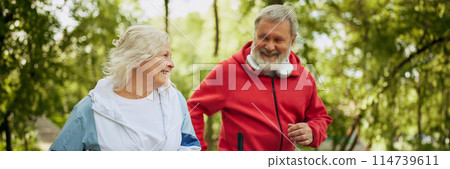 Sport inspirational. Happy smiling elderly people, man and woman in sportswear jogging in public park in early morning. Banner Sport inspirational. Happy smiling elderly people, man and woman in sportswear jogging in public park in early morning. Banner 114739611
