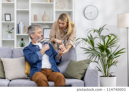 Woman and man having an intense conversation after seeing a message on a smartphone while sitting on a couch. Woman and man having an intense conversation after seeing a message on a smartphone while sitting on a couch. 114740001