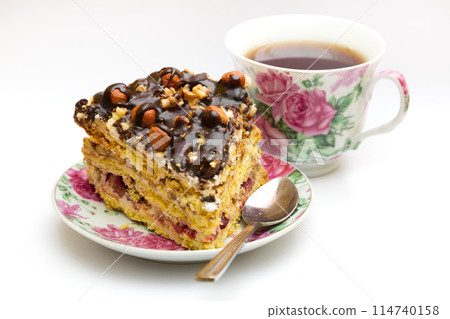 Piece of cake with hazelnuts, teaspoon and cup 114740158