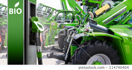 Biofuel filling station on a background of green construction machines. Decarbonization of heavy industrial vehicles Biofuel filling station on a background of green construction machines. Decarbonization of heavy industrial vehicles 114740404