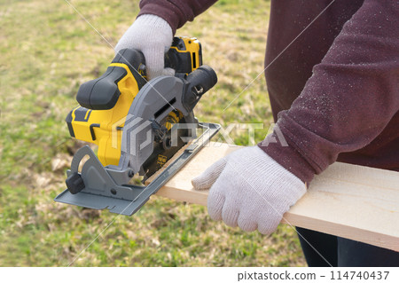 Man sawing board with a circular saw. High quality photo Man sawing board with a circular saw. High quality photo 114740437