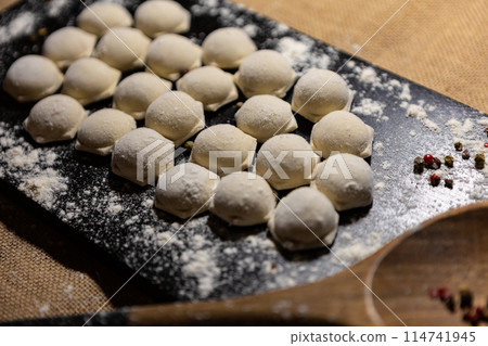 Traditional russian pelmeni, ravioli, dumplings with meat on black wood background. Top view. Copy space Traditional russian pelmeni, ravioli, dumplings with meat on black wood background. Top view. Copy space 114741945