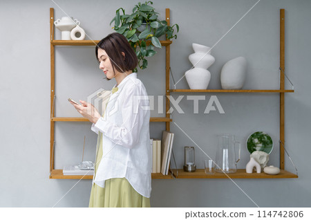 Young woman looking at her smartphone in her room 114742806