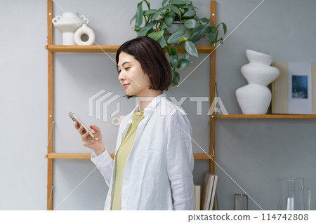 一位年輕女子在房間裡看著她的智慧型手機 114742808