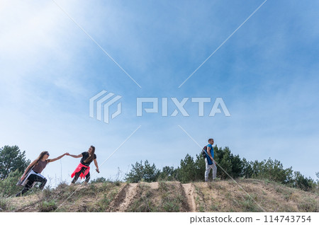 A girl helps another girl up a hill. A girl helps another girl up a hill. 114743754