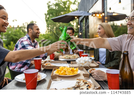 Young people enjoying leisure time together outside toasting with beer 114743885