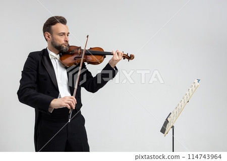 Accomplished violinist guided by sheet music performing classical music Accomplished violinist guided by sheet music performing classical music 114743964