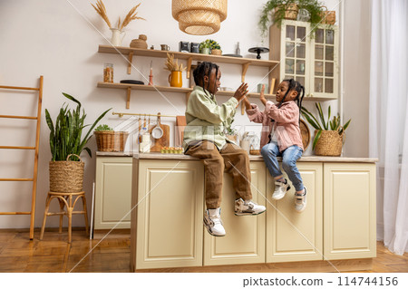Small adorable multiethnic girls playing in kitchen enjoying weekend spending together Small adorable multiethnic girls playing in kitchen enjoying weekend spending together 114744156