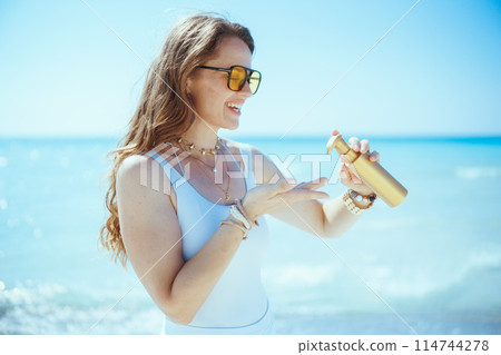 smiling stylish 40 years old woman on seashore with spf 114744278