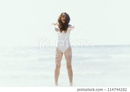 smiling elegant woman on beach having fun time in water 114744282