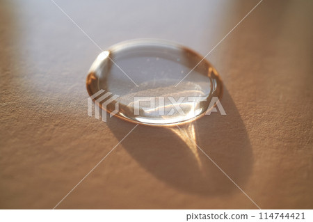 Beautiful volumetric drop of cosmetic product on a beige background. Beautiful volumetric drop of cosmetic product on a beige background. 114744421