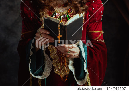 Closeup on medieval queen in red dress with book and rosary Closeup on medieval queen in red dress with book and rosary 114744507