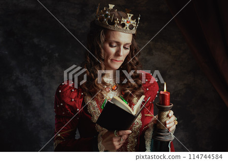 stressed medieval queen in red dress with book and candle stressed medieval queen in red dress with book and candle 114744584