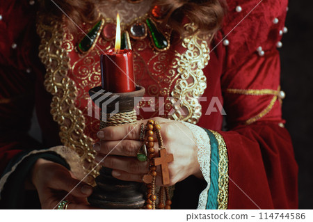 Closeup on medieval queen in red dress with candle 114744586