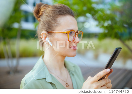 pensive woman employee in green blouse and eyeglasses 114744720