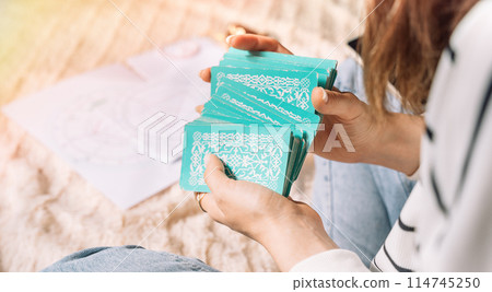 Lady shuffling tarot cards with green cover 114745250