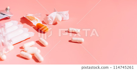 Rectal candles in packaging and unpacked and ointment in a tube on a pink background Rectal candles in packaging and unpacked and ointment in a tube on a pink background 114745261