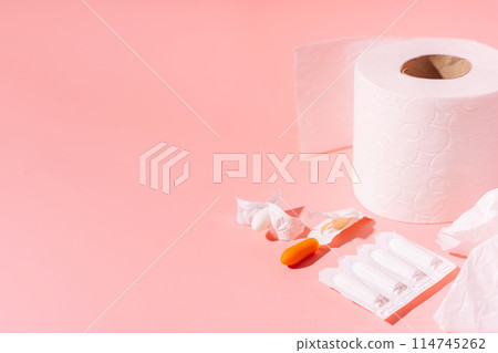 Rectal candles in packaging and unpacked and toilet paper on a pink background 114745262