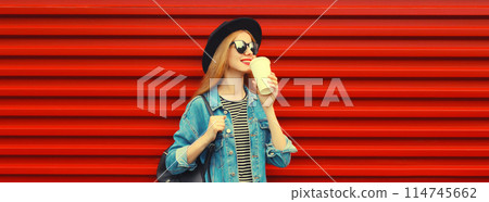 Beautiful stylish happy young woman with cup of coffee wearing black round hat on red background 114745662