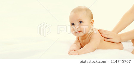 Mother gives massage to baby lying on the bed on white background 114745707