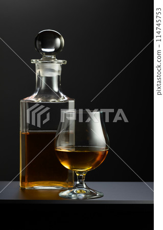 Old decanter and glass with whiskey, cognac or brandy. 114745753