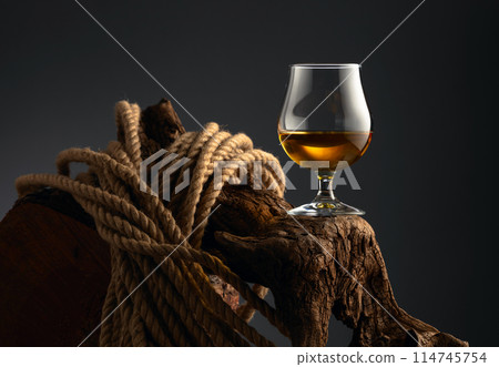 Brandy snifter and rope on a old wooden snag. 114745754