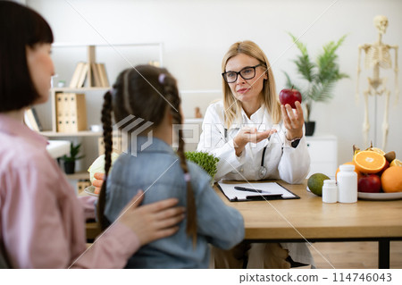 Mature woman with apple chatting with little female child and her mother. 114746043