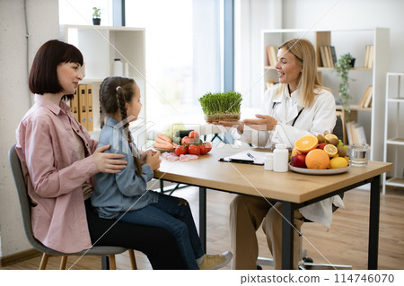 Little girl sitting on mother lap at appointment with mature female nutritionist 114746070