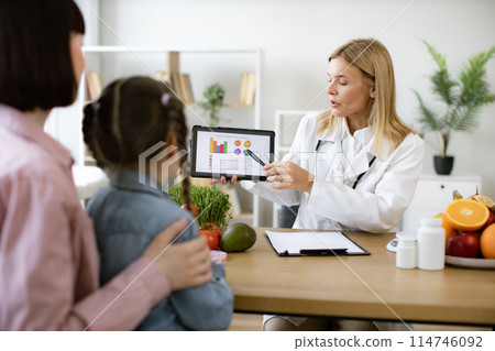 Mature Caucasian female doctor shows on tablet graphs of food for healthy eating 114746092