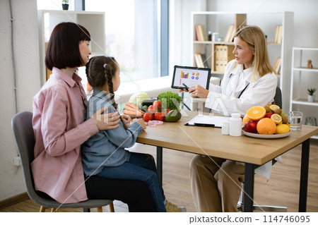 Mature Caucasian female doctor shows on tablet graphs of food for healthy eating 114746095