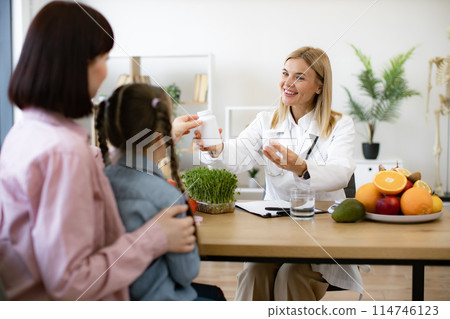 Happy pretty female nutritionist holding bottles with pills. Happy pretty female nutritionist holding bottles with pills. 114746123
