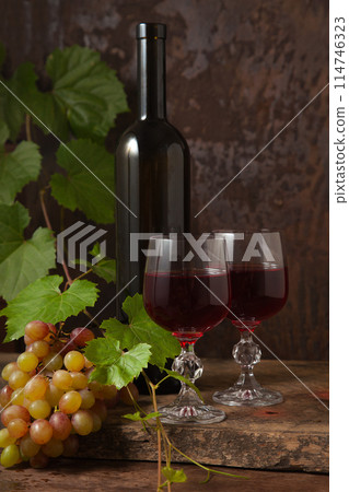 Still life with glasses of red wine and grapes on vintage wooden background.. Still life with glasses of red wine and grapes on vintage wooden background.. 114746323