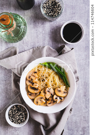 Asian soup with rice noodles, mushrooms and green onions in a bowl top and vertical view Asian soup with rice noodles, mushrooms and green onions in a bowl top and vertical view 114746604