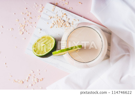 Close up of homemade oatzempic drink of oat milk and lime in a glass on the table top view Close up of homemade oatzempic drink of oat milk and lime in a glass on the table top view 114746622