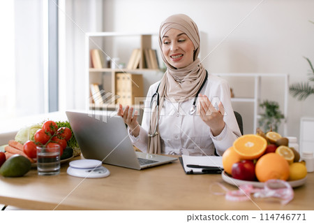 Muslim female making video call via wireless device at doctor's workplace. Muslim female making video call via wireless device at doctor's workplace. 114746771